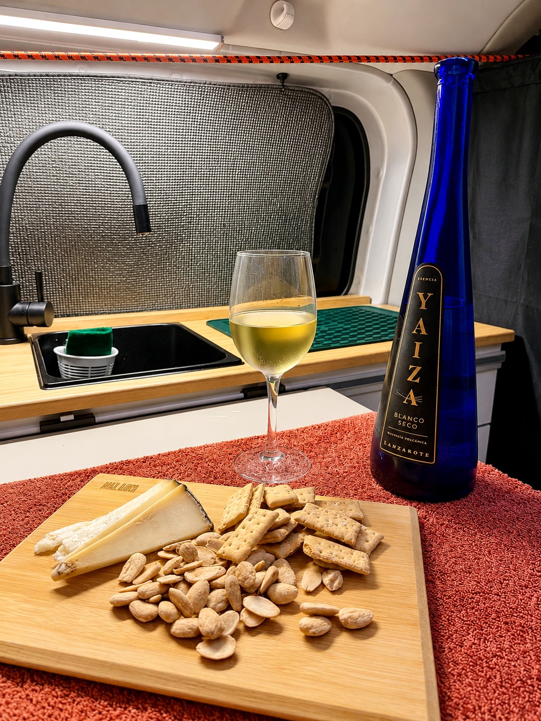 Rincón de la cocina de la camper con vino y queso